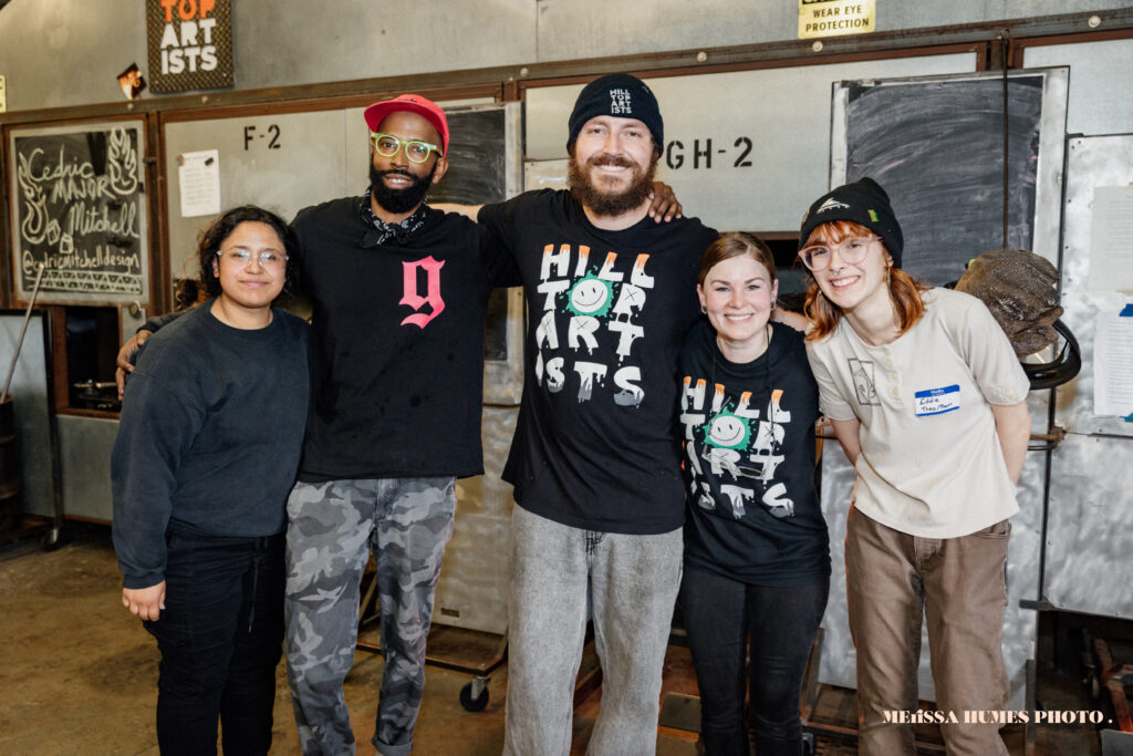 Hilltop Artists staff and students pose with visiting artist, Cedric Mitchell, during the 2023 Spring Glass Sale. Image courtesy of Merissa Humes Photo